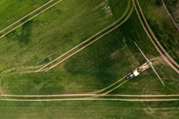 Vista aerea del trattore che spruzza i prodotti chimici sul grande campo verde