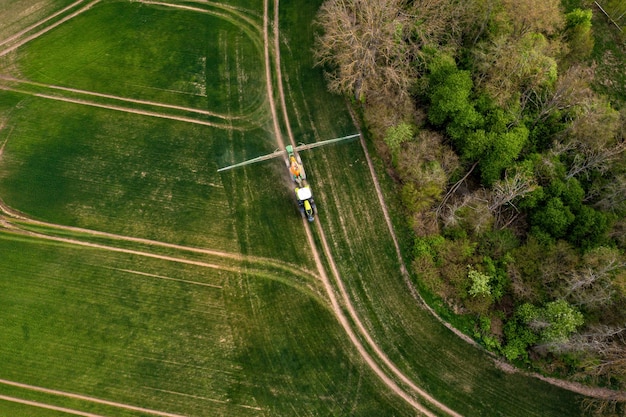 Vista aerea del trattore che spruzza i prodotti chimici sul grande campo verde