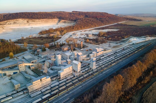 Vista aerea del treno merci caricato con pietrisco presso una fabbrica mineraria. Trasporto ferroviario di minerale calcareo macinato.