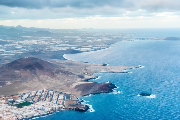 Vista aerea dell'aeroplano del paesaggio costiero e della città di Arinaga sull'isola di Gran Canaria con le colline e le città dell'oceano