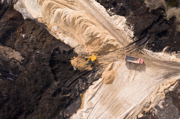 Vista aerea dell'escavatore e del camion che lavora al cantiere.