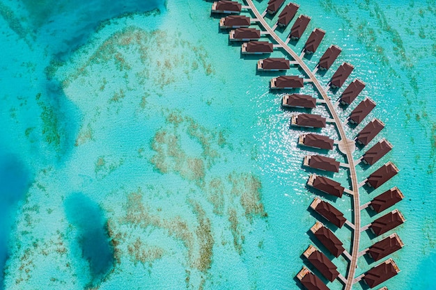 Vista aerea dell'isola delle Maldive, resort di ville sull'acqua di lusso e molo in legno. Splendida laguna oceanica