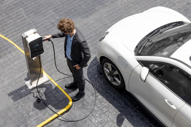 Vista aerea dell'uomo d'affari progressivo con la batteria di ricarica per auto EV