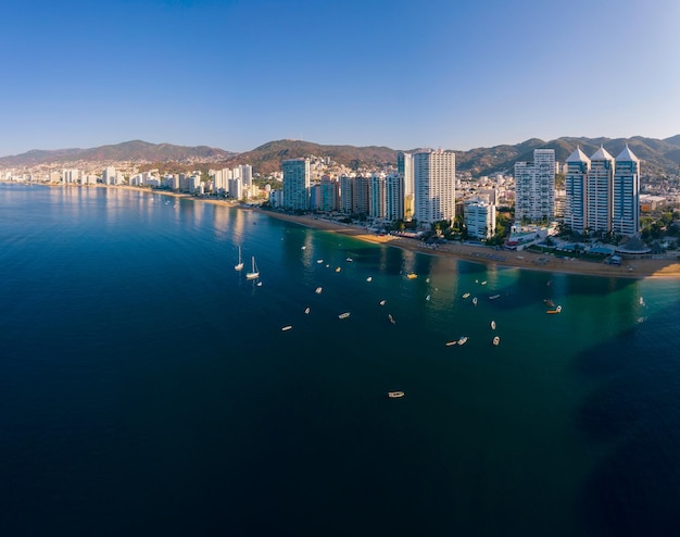 Vista aerea della baia di Acapulco con barche che navigano sulle calme acque blu scuro in una giornata di sole