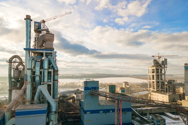 Vista aerea della cementeria con alta struttura di fabbrica e gru a torre nell'area di produzione industriale.