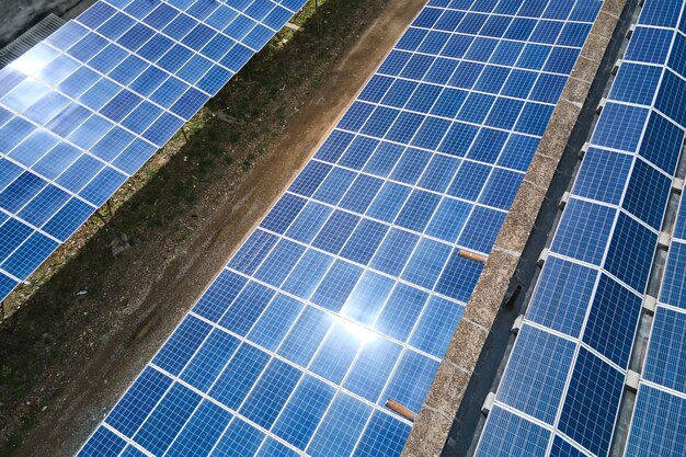 Vista aerea della centrale solare con pannelli fotovoltaici blu montati sul tetto di un edificio industriale per la produzione di elettricità ecologica verde. Produzione del concetto di energia sostenibile.