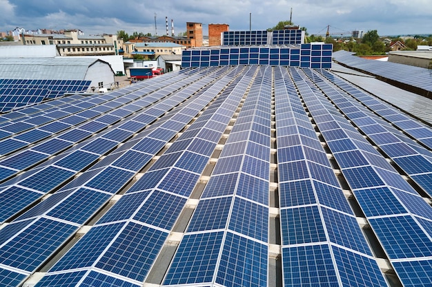 Vista aerea della centrale solare con pannelli fotovoltaici blu montati sul tetto di un edificio industriale per la produzione di elettricità ecologica verde Produzione di un concetto di energia sostenibile