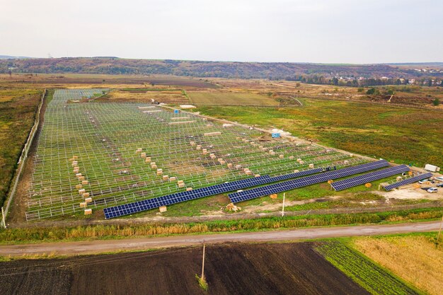 Vista aerea della centrale solare in costruzione sul campo verde. Assemblaggio di quadri elettrici per la produzione di energia pulita ed ecologica.