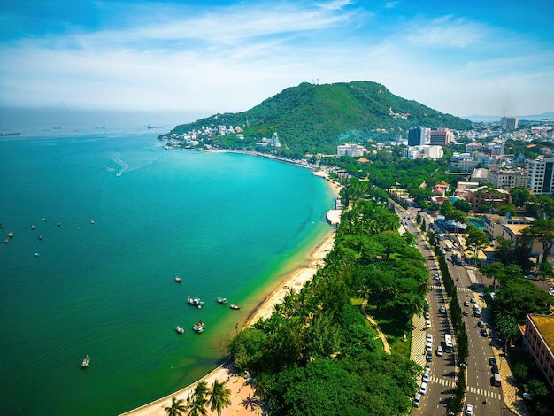 Vista aerea della città di Vung Tau con bel tramonto e tante barche Vista panoramica costiera di Vung Tau dall'alto con onde lungo la costa, alberi di cocco e montagna Tao Phung in Vietnam