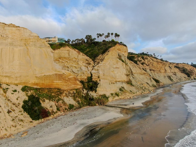 Vista aerea della costa pacifica con scogliere di arenaria gialla e onde che si precipitano sulla spiaggia