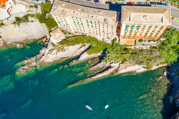 Vista aerea della costa rocciosa di Camogli. Le barche e gli yacht hanno attraccato vicino al porto con acqua verde.