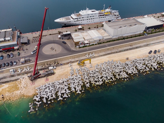 Vista aerea della costruzione del frangiflutti Bulldozer e gru su un mucchio di massi nel mare