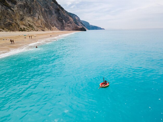 Vista aerea della donna della spiaggia della Grecia che galleggia sull'anello gonfiabile