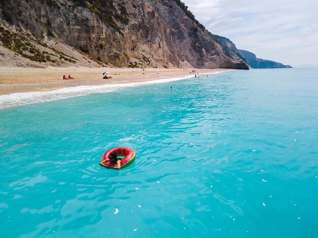 Vista aerea della donna della spiaggia della grecia che galleggia sullo spazio della copia dell'anello gonfiabile