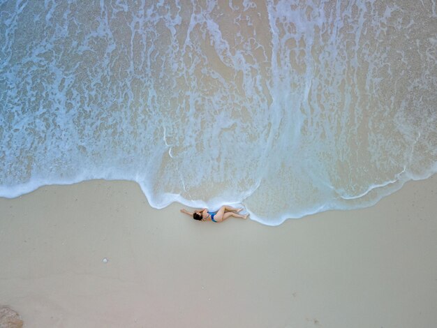 Vista aerea della donna in costume da bagno blu in mare spiaggia belle onde