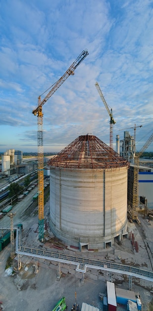 Vista aerea della fabbrica di cemento in costruzione con struttura ad alta struttura in calcestruzzo e gru a torre nell'area di produzione industriale Fabbricazione e concetto di industria globale