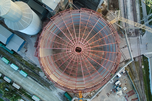 Vista aerea della fabbrica di cemento in costruzione con struttura in calcestruzzo alta e gru a torre nell'area di produzione industriale. Produzione e concetto di industria globale.