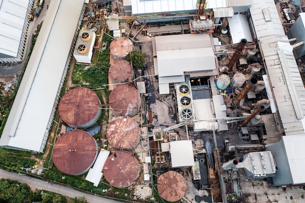 Vista aerea della fabbrica di lavorazione della raffineria di etanolo industriale o di biocarburante con fumo dal camino, serbatoi di stoccaggio e magazzino. Problema di inquinamento climatico e riscaldamento globale