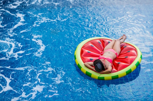 Vista aerea della femmina in bikini che si trova su un materasso galleggiante in piscina.