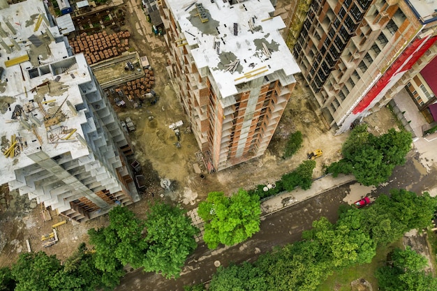Vista aerea della gru di sollevamento a torre e del telaio in cemento di alti edifici residenziali in costruzione in una città Sviluppo urbano e concetto di crescita immobiliare