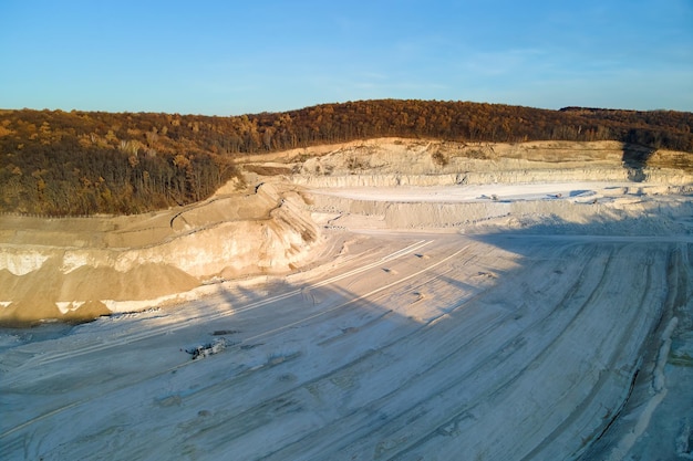 Vista aerea della miniera a cielo aperto di materiali in arenaria per l'edilizia con escavatori e autocarri con cassone ribaltabile. Attrezzature pesanti nell'estrazione mineraria e nella produzione di minerali utili concept