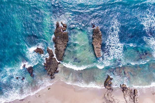 Vista aerea della riva dell'oceano con onde che si infrangono sulle rocce e spiaggia con sabbia bianca