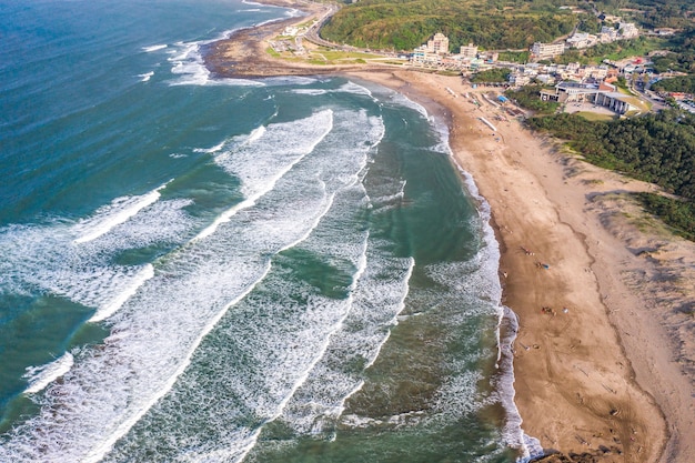 Vista aerea della spiaggia di sabbia con i turisti che nuotano nell'acqua del mare cristallino
