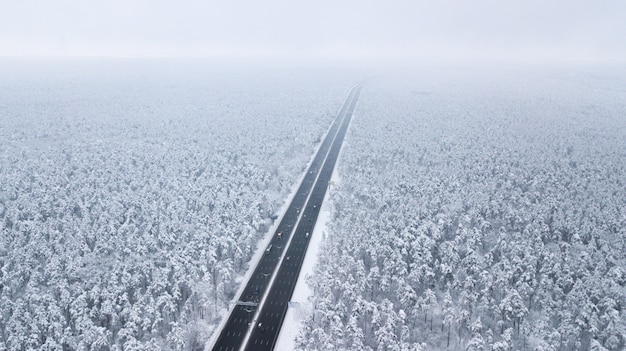 Vista aerea della strada innevata nella foresta di inverno, camion che passa vicino, mosso