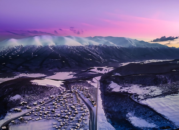 Vista aerea delle case stradali delle montagne innevate e del cielo viola