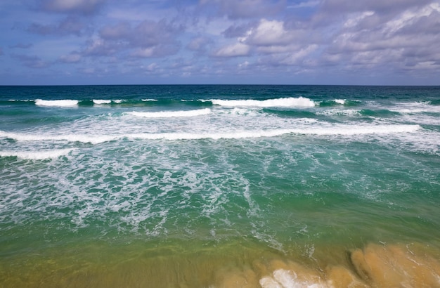 Vista aerea delle onde che si infrangono sul mare Onde schiumose bianche sulla sabbia della spiaggia Vista dall'alto vista sul mare della spiaggia Natura mare oceano sfondo