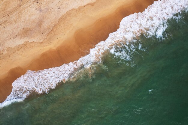 Vista aerea delle onde che si infrangono sul mare Onde schiumose bianche sulla sabbia della spiaggia Vista dall'alto vista sul mare della spiaggia Sfondo della natura