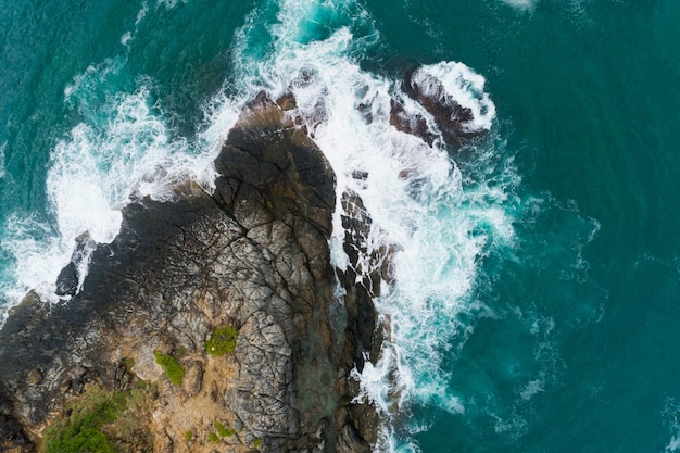 Vista aerea delle onde che si infrangono sul mare Onde schiumose bianche sulle rocce del mare Vista dall'alto fantastica costa rocciosa Sfondo di natura stupefacente.