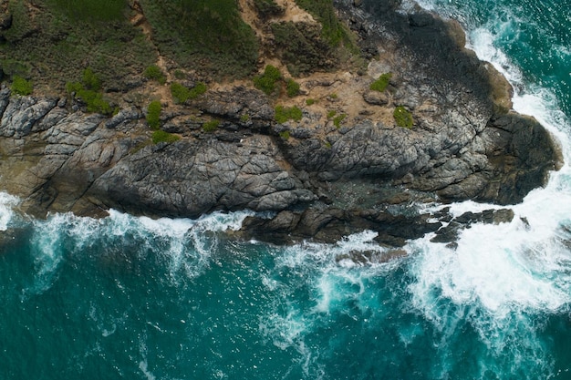 Vista aerea delle onde che si infrangono sul mare Onde schiumose bianche sulle rocce in riva al mare Vista dall'alto Costa rocciosa.