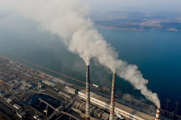 Vista aerea di alte canne fumarie con fumo grigio dalla centrale elettrica a carbone. Produzione di energia elettrica con combustibili fossili.