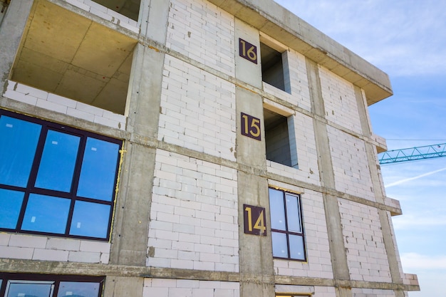 Vista aerea di alto edificio residenziale con numeri di piano sulla parete in costruzione. Sviluppo immobiliare.