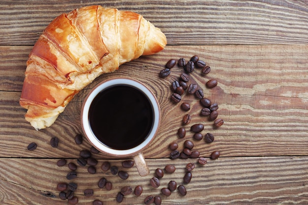 Vista aerea di caffè nero e croissant sul tavolo di legno