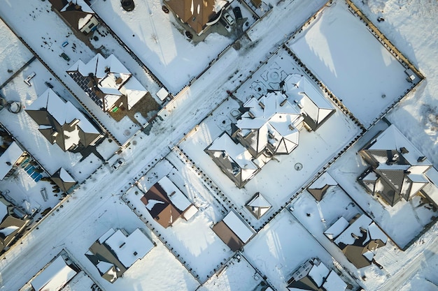 Vista aerea di case private con tetti coperti di neve nelle periferie rurali della zona cittadina in inverno freddo