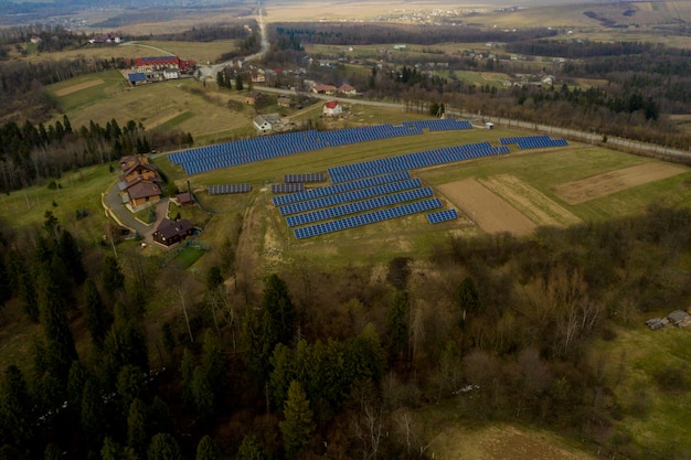 Vista aerea di grande campo del sistema fotovoltaico solare dei pannelli fotovoltaici che producono energia pulita rinnovabile sul fondo dell'erba verde.