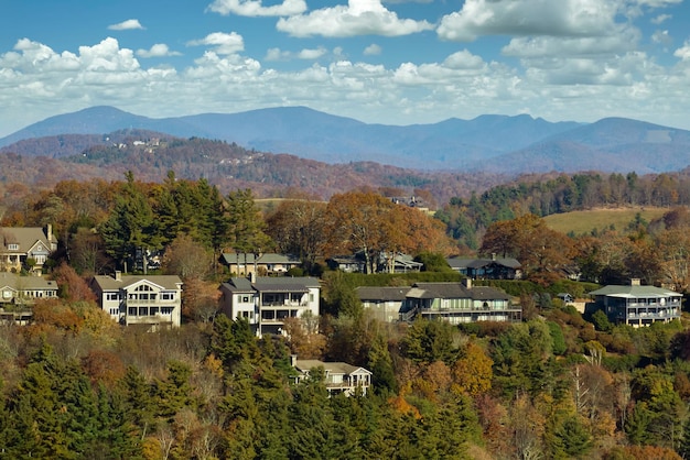 Vista aerea di grandi case familiari sulla cima di una montagna tra alberi gialli nell'area suburbana della Carolina del Nord nella stagione autunnale Sviluppo immobiliare nella periferia americana