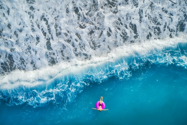 Vista aerea di nuoto della giovane donna sull'anello rosa di nuotata