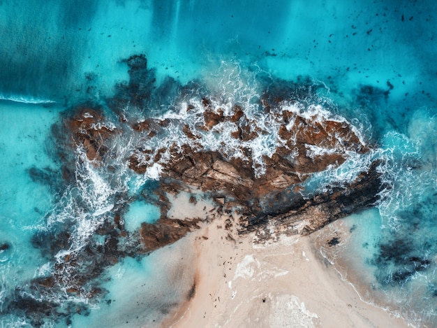 Vista aerea di onde, rocce e mare trasparente