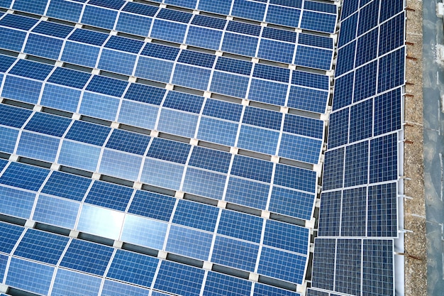 Vista aerea di pannelli solari fotovoltaici blu montati sul tetto di un edificio industriale per la produzione di elettricità ecologica verde. Produzione del concetto di energia sostenibile.