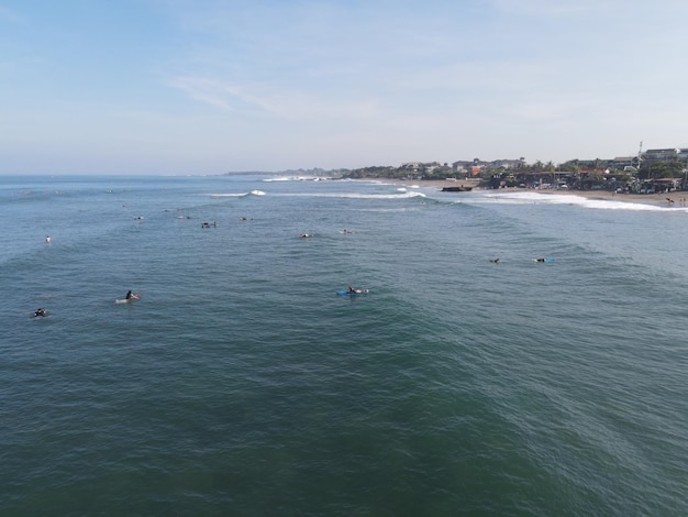 Vista aerea di persone che navigano sulle onde con le tavole da surf durante le vacanze a Bali Indonesia