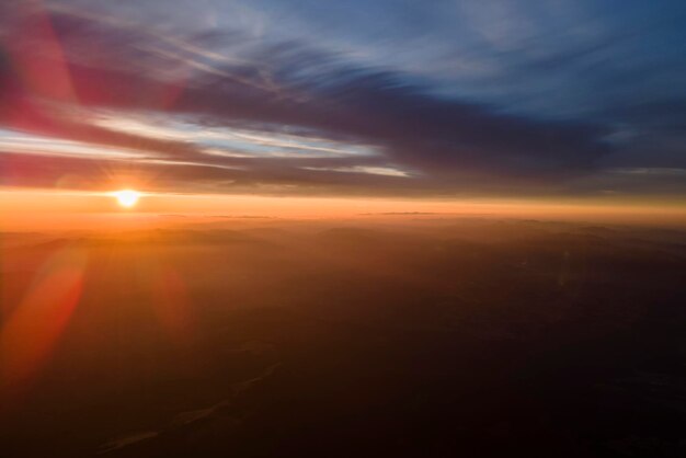 Vista aerea di scure colline di montagna con raggi luminosi del sole al tramonto Cime nebbiose e valli nebbiose in serata