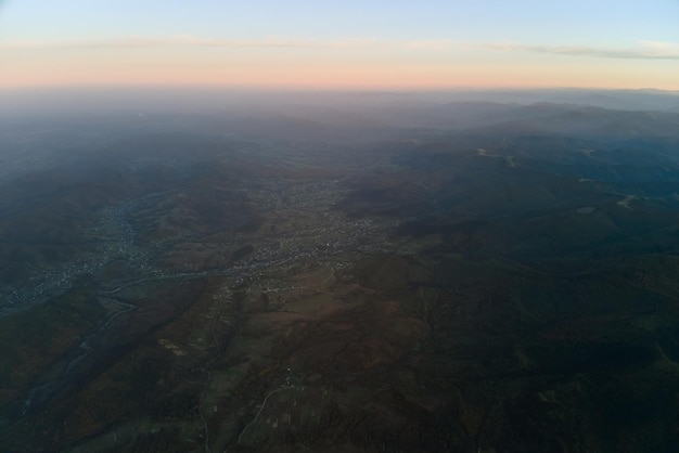 Vista aerea di scure colline di montagna con raggi luminosi del sole al tramonto Cime nebbiose e valli nebbiose in serata