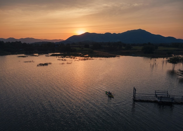 Vista aerea di turisti che remano in canoa sul lago e tramonto sulla vista sulle montagne