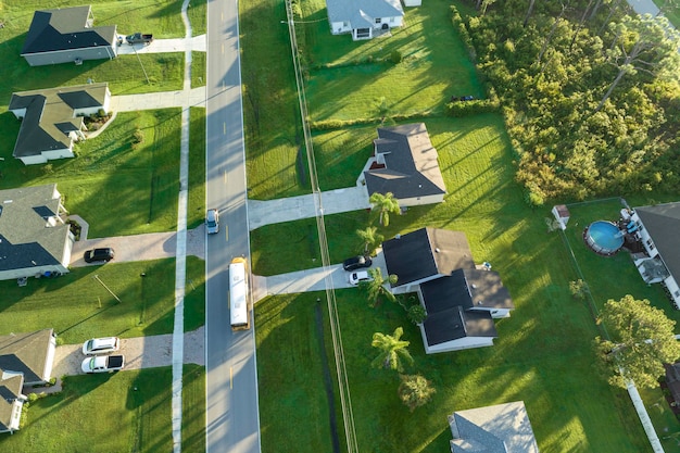 Vista aerea di un autobus scolastico giallo americano che guida su una strada suburbana per prendere i bambini per le loro lezioni al mattino presto Trasporto pubblico negli Stati Uniti