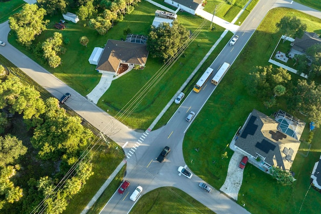 Vista aerea di un autobus scolastico giallo americano che raccoglie i bambini alla fermata dell'autobus sul marciapiede per le loro lezioni al mattino presto Trasporto pubblico negli Stati Uniti