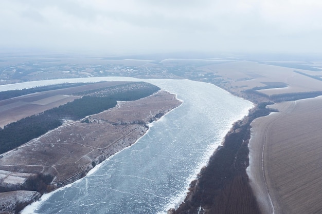 Vista aerea di un fiume coperto di gelate forti di ghiaccio paesaggio invernale rurale di un fiume tortuoso e campi