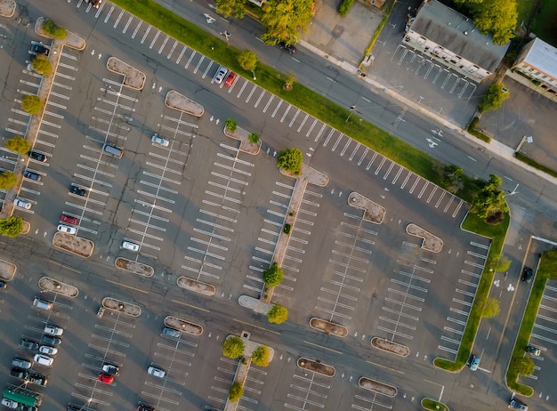 Vista aerea di un gran numero di auto di diverse marche in piedi parcheggio vicino al centro commerciale nel parcheggio diviso da strisce divisorie bianche e marciapiedi